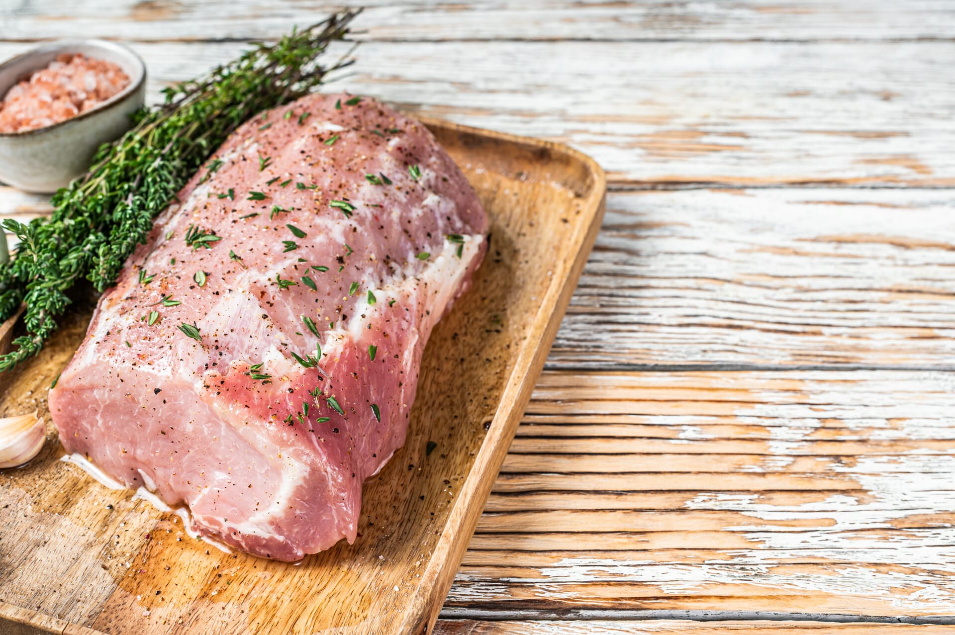 Raw Whole boneless pork loin meat with thyme and salt on rustic cutting board, created by Oklahoma Pork Processors